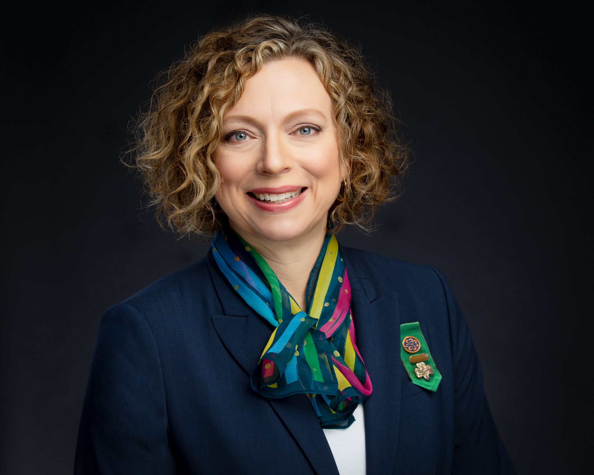 Headshot of CEO Paula Bookitis wearing navy blazer and colorful scarf